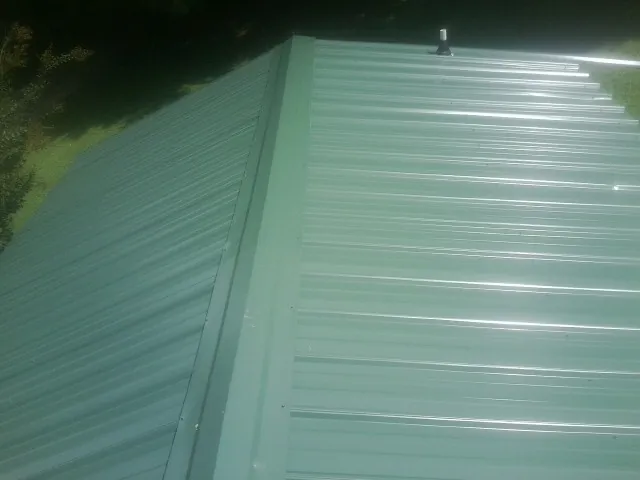 New green metal panels meeting at the ridge of a roof — Flat Roof Repair work by our crew in Midland