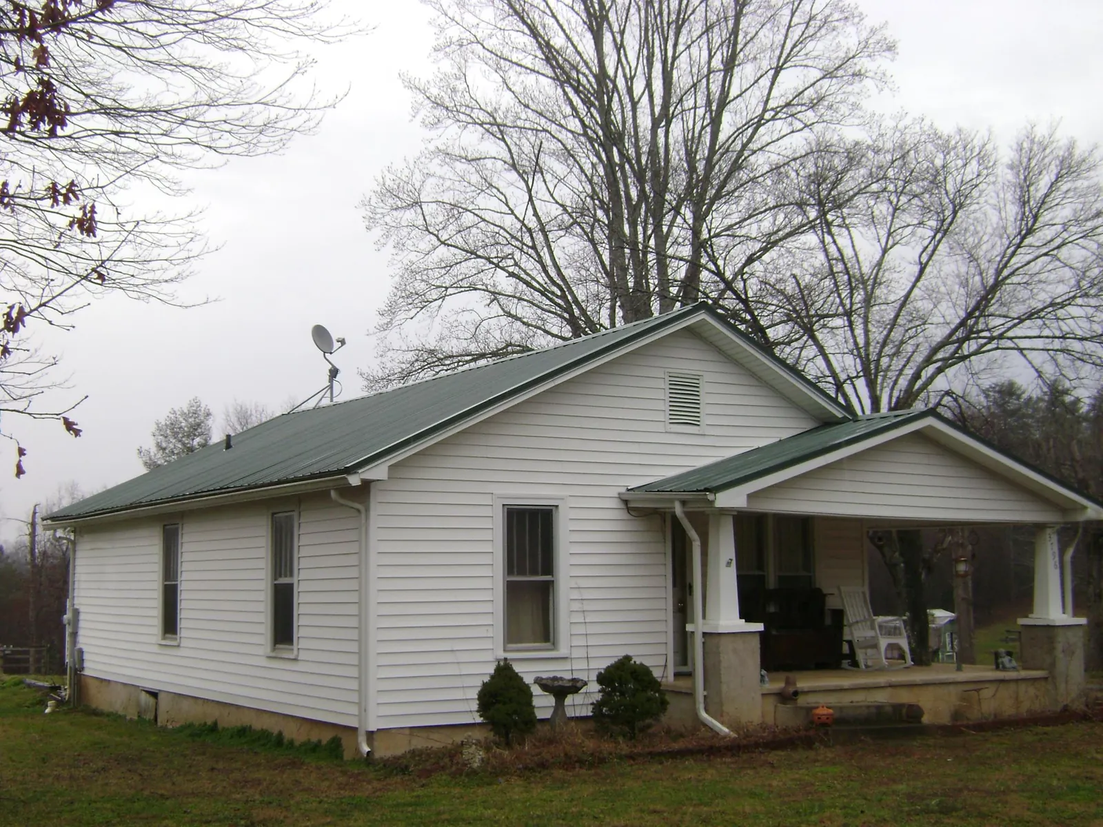 Green metal roof on a white bungalow with a side porch in Midland