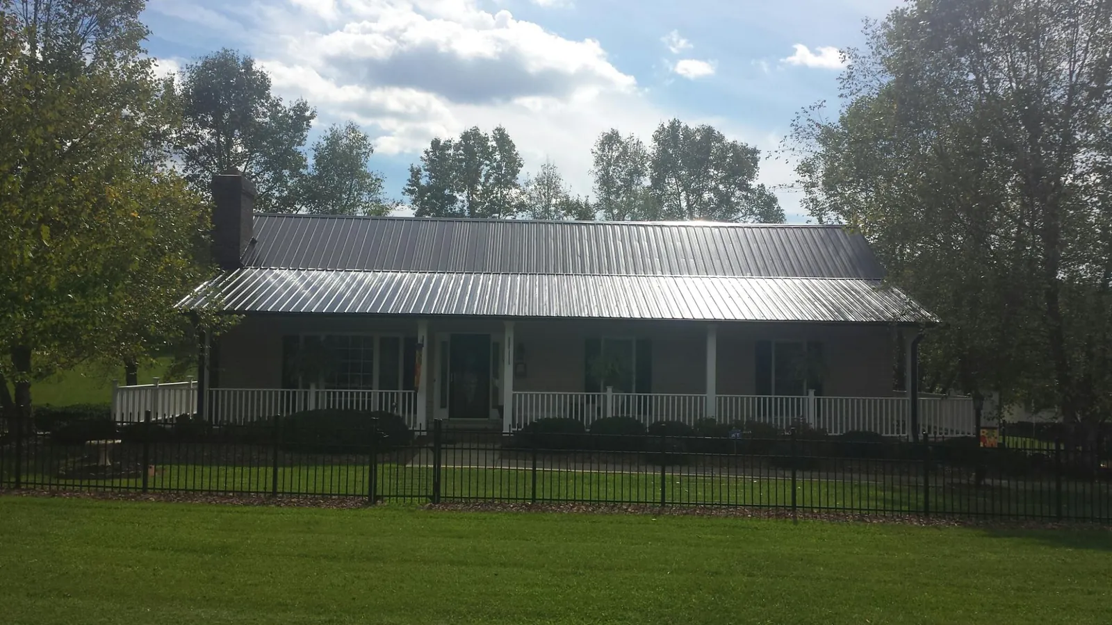 Gray metal roof on a brick ranch with a full width front porch — Gutter Guard Installation work by our crew in Midland